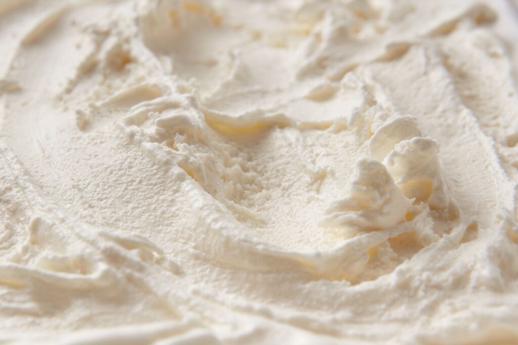 Gros plan détaillé de la texture crémeuse de la glace blanche, mettant en avant sa consistance lisse et douce.